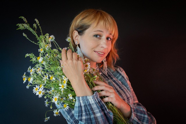 A young woman holding a bunch of wild flowers. Image by Victoria from Pixabay.